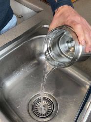 an image of a clean insulated food container having the boiling water tipped out in a sink