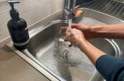 a person washing their hands with soap in a sink with running water